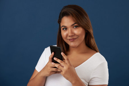 Young woman using smartphone isolated on blue studio background