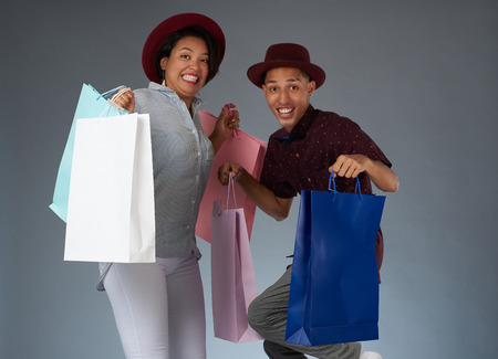 Funny jumping shopaholic couple isolated on studio backgroundの写真素材