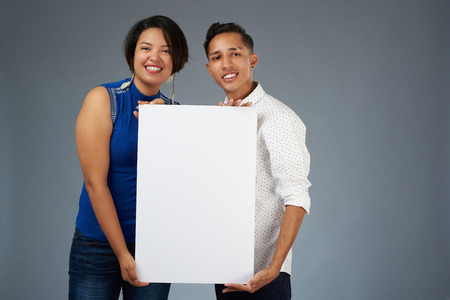 Young couple hold white banner isolated on studio backgroundの写真素材