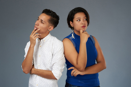 Young couple thinking on problem isolated on gray studio backgroundの写真素材