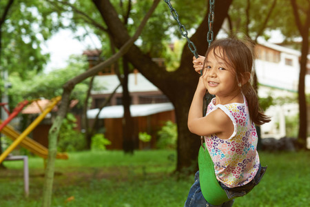 Asian girl on a swing looking at the camera. Filipina girl. 6 to 7 years old.の写真素材
