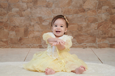 One baby girl in yellow dress smiling and clappingの写真素材