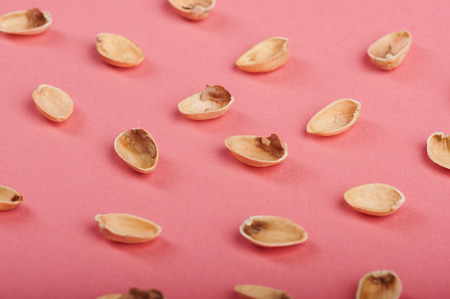 Empty pistachio shells on pink paper backgroundの写真素材