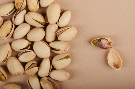 One open pistachio on brown paper background with group on sideの写真素材