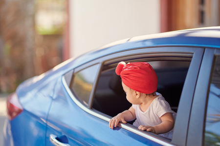 Little baby looking back from car windowの写真素材