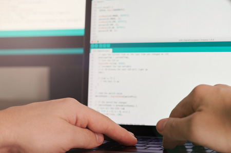 Software developing theme. Hands on laptop keyboard in blurred monitor backgroundの写真素材