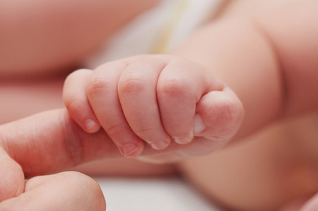 Small baby hand hold father finger close up viewの写真素材