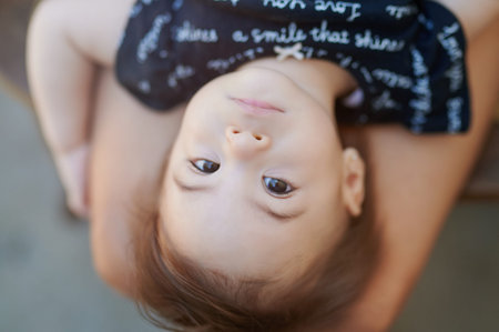 Portrait of cute baby girl lay on laps and look in camera