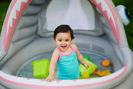 Baby girl play in inflatable gray pool aloneの写真素材