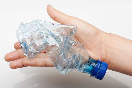 Recycling plastic theme. Crushed blue plastic bottle in hand palmの写真素材