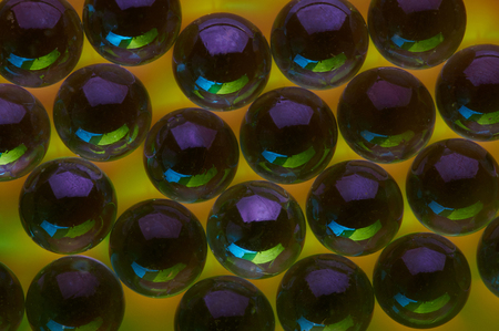 Dark glass balls on yellow background close up viewの写真素材