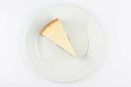One piece of cheesecake on plate above top view isolatedの写真素材