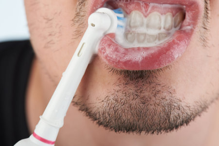 Brushing healthy teeth with electric toothbrush close up view
