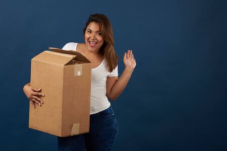 Teenager girl with big package box isolated on blue studio backgroundの写真素材