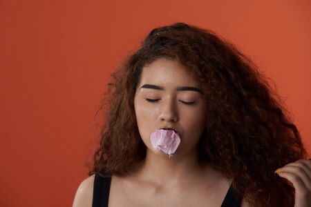Woman with exploded bubble gum ball on her lips portraitの写真素材
