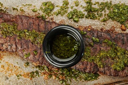 Chimichurri sauce in bowl on bbq meat backgroundの写真素材
