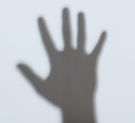 Shadow of hand palm on white wall background
