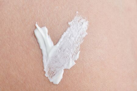 Check sign from white skin cream on clean beige color backgroundの写真素材