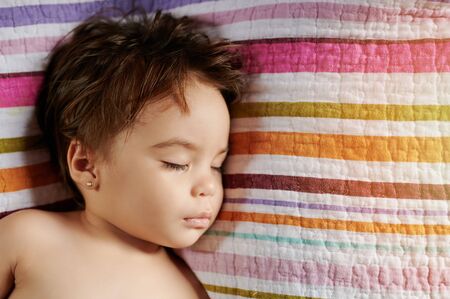 Face of sleeping baby on colorful striped backgroundの写真素材