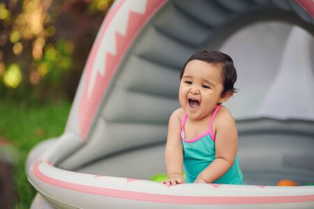 Cute baby girl having fun in inflatable swimming poolの写真素材