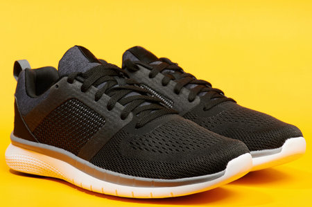 Pair of modern black running shoes on yellow bright backgroundの写真素材