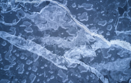 Frosty lake surface above drone top view. Pattern of blue ice