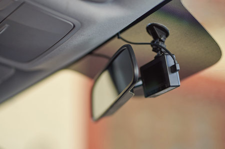 Small black car camera on windshield behind mirror