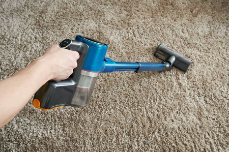 Cleaning carpet with vacuum cleaner on gray background