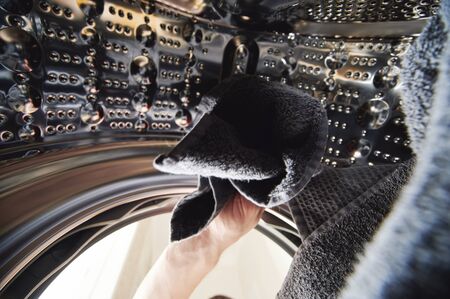 Laundry housework theme. Hand putting dirty cloth into washinr machineの写真素材