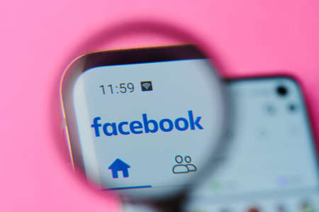 New-York , USA - June 4 , 2020: Using facebook app on modern smartphone throw magnifier close up viewのeditorial素材