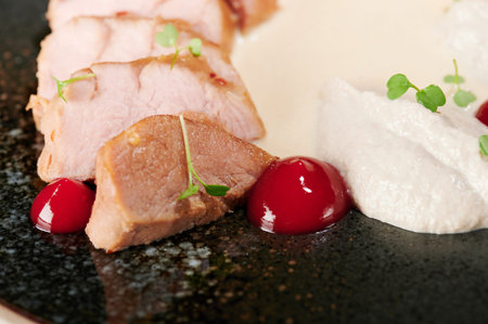 Juicy cooked pork meat with white sauce and herbsの写真素材