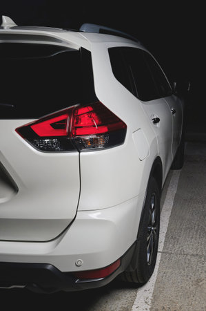 Back side view of white modern SUV car in black background