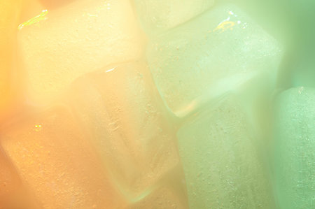 Pattern of green and yellow ice cubes close up view. Clear melt ice