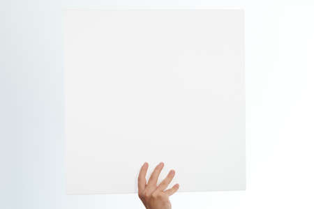 One hand hold white board isolated on studio backgroundの写真素材