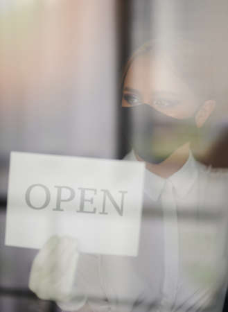Young woman in face mask open business after lockdownの写真素材