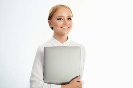 Portrait of girl smiling and holding laptop isolated on white studio backgroundの写真素材