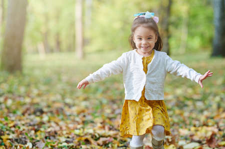 Girl having fun in autumn park. Running toddler outsideの写真素材