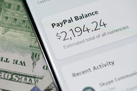 New york, USA - January 5, 2021: Using paypal for purchase  with smartphone on dollar banknote...
