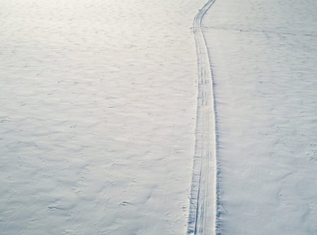 Winter car path in snowy field aerial above drone view