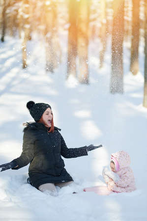 Happy playing with snow family on bright sunny winter dayの写真素材