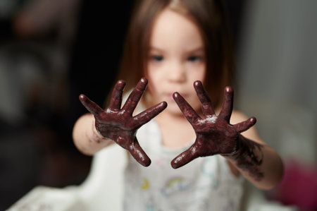 Girl child palm hands painted  in dark brown color. Play messy with paint theme