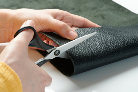 Cutting black leather with scissors  macro close up view