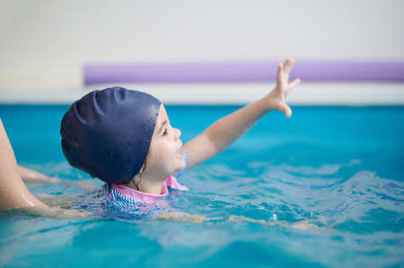 Child learn to swim in pool with teacher help. Swimming exercise themeの写真素材