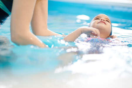 Teacher help to child swim on back in blue pool waterの写真素材