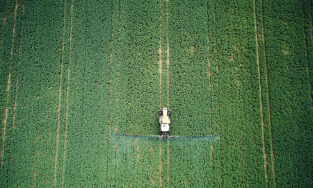 Tractor spraying pesticides on green meadow above top drone view. Agriculture themeの写真素材