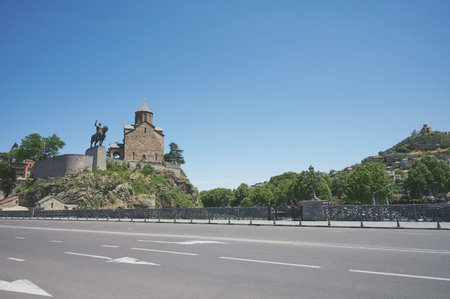 Old chruch with statue in Tbilisi with green park on blue sky background