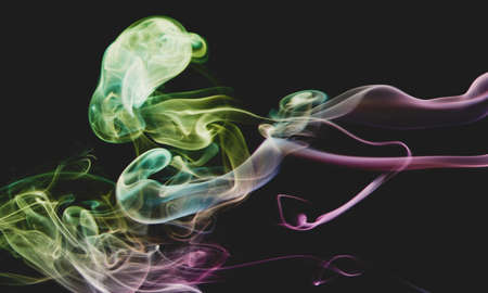 Cloud of rainbow color smoke swirls on dark grey backdrop close up viewの写真素材
