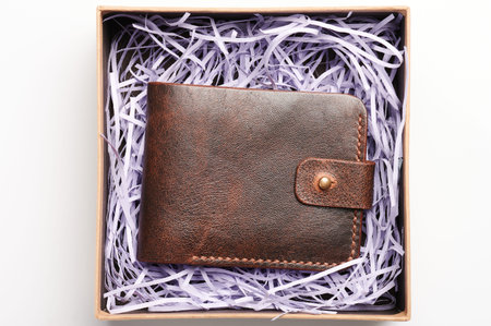 Genuine leather  brown wallet in paper open box above top view isolated