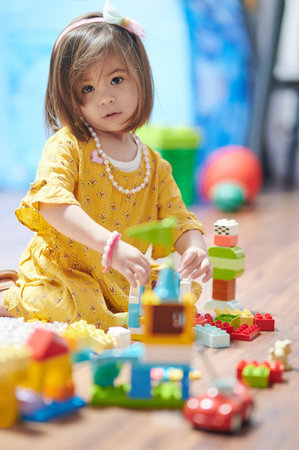Pretty child girl playing with colorful blocks in houseの写真素材