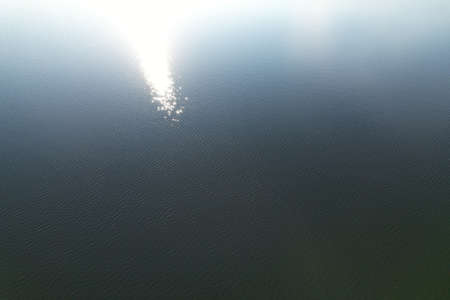 Lake water surface with ripples and sun reflection aerial viewの写真素材